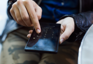Hender som holder en mobiltelefon og taster PIN-kode.